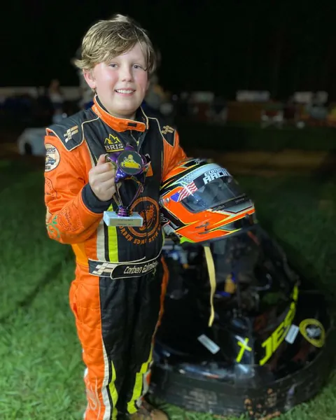 Young driver Alex in a custom orange and black suit at the track