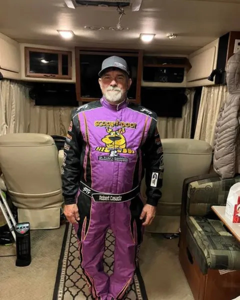A driver in a custom purple and black suit indoors