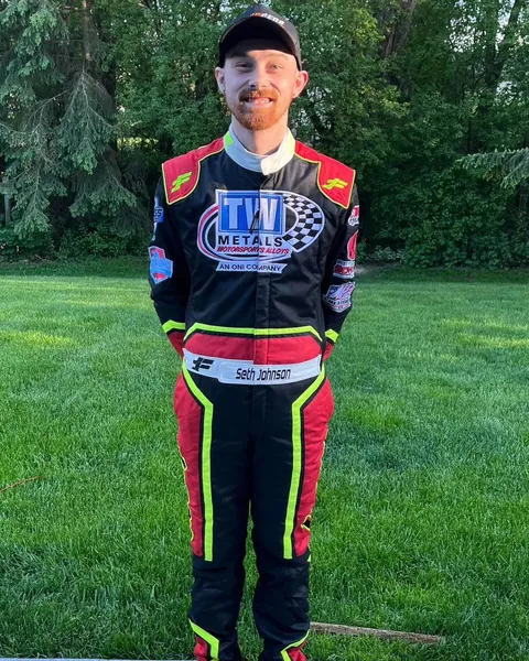 Seth Johnson in a custom black suit with red and green trim, standing on a lawn