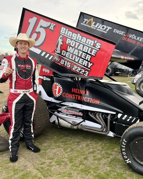A driver in a cowboy hat and custom suit beside his number 15 sprint car
