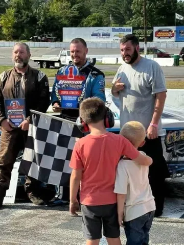 A racing family celebrating in victory lane with the checkered flag